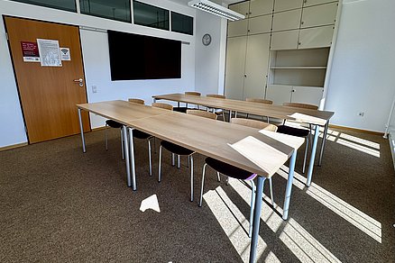 Zwei Tischreihen hintereinander zu je vier Stühlen