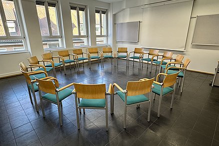 Geschlossener Stuhlkreis mit achtzehn Stühlen