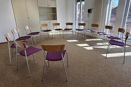 Offener Stuhlkreis mit zehn Stühlen